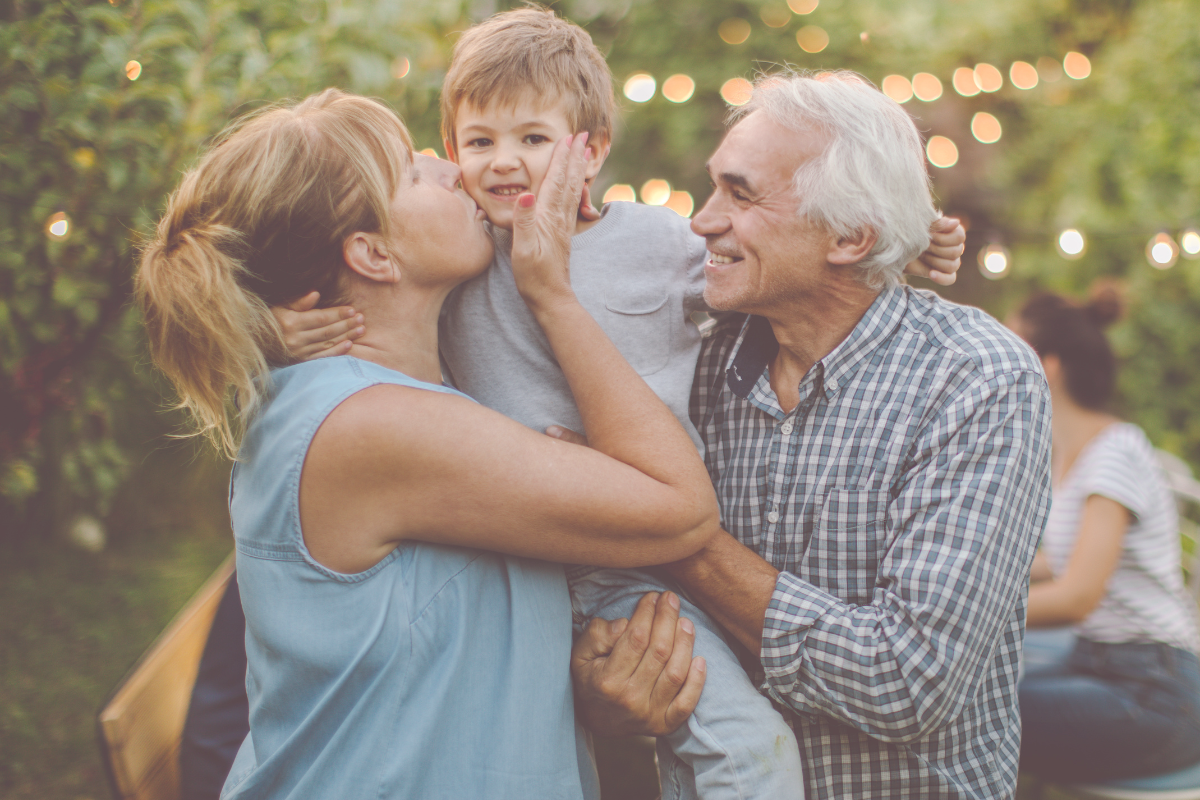 Enfant dans les bras de son grand-père et de sa mère qui l'embrasse